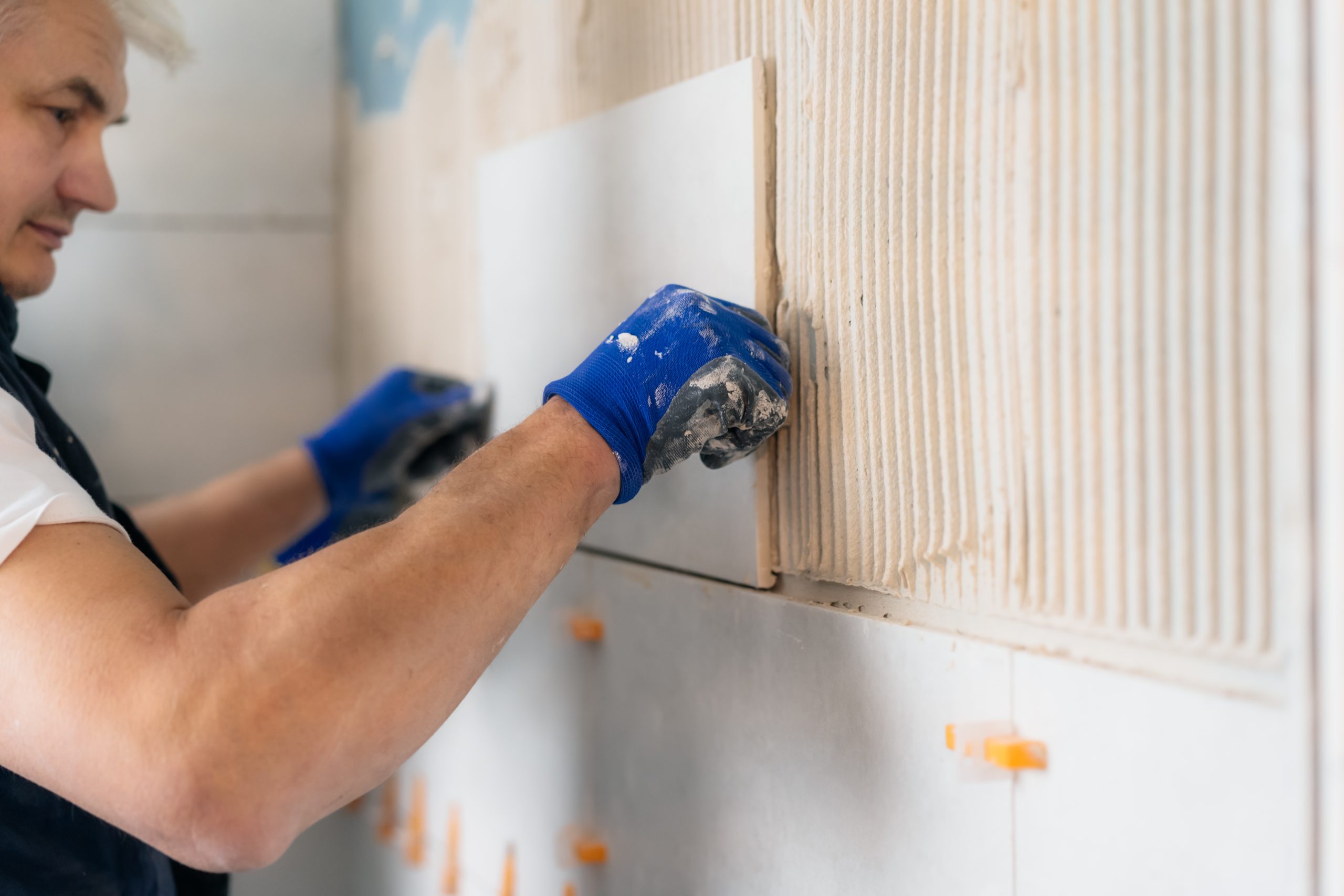 man-laying-tiles-on-a-bathroom-wall-diy-concept-2022-11-09-17-44-25-utc-scaled
